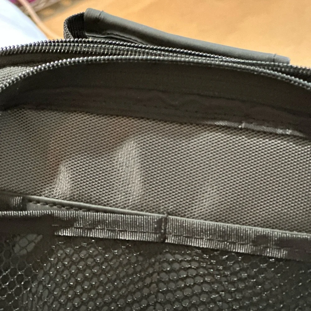 Canon black camera bag with zipper packets, and a handle at the top.